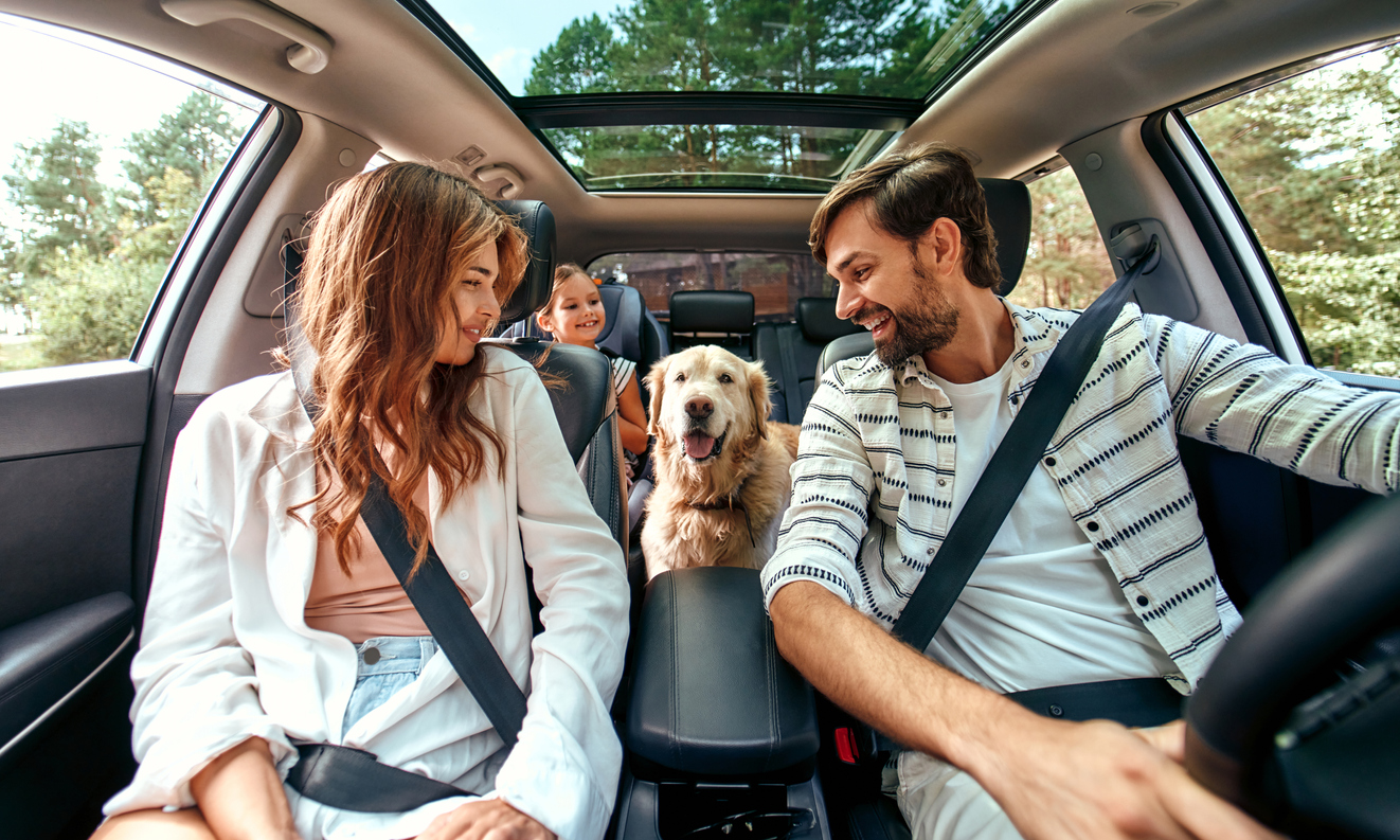 Happy family with a golden retriever dog and kids driving in a car together